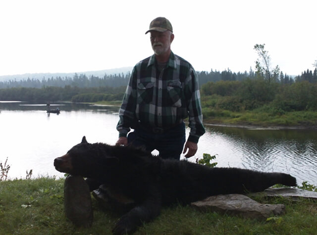 up close photo of man posing with killed black bear