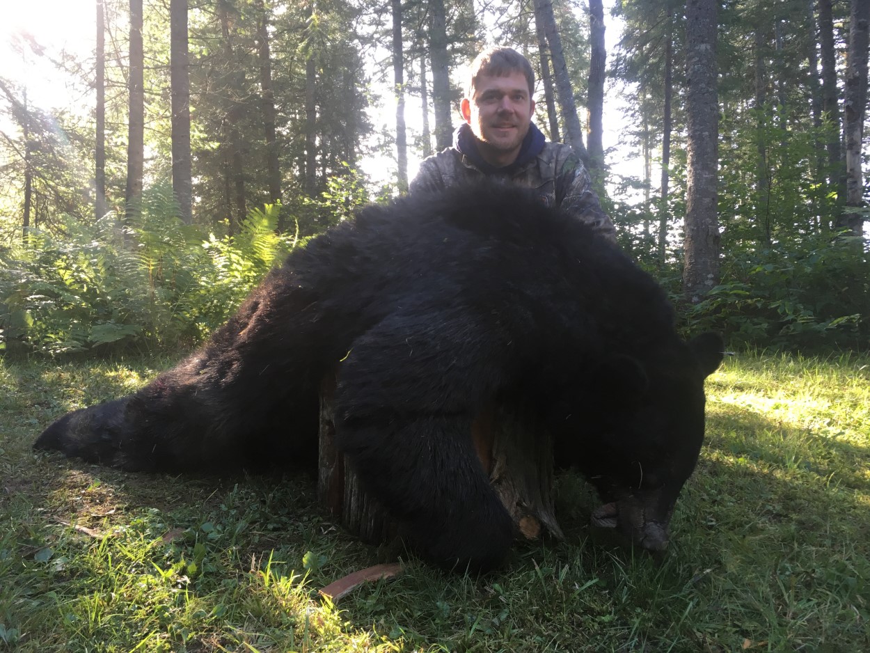young man in camo posing with rifle and killed black bear