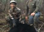 father and son posing with killed black bear