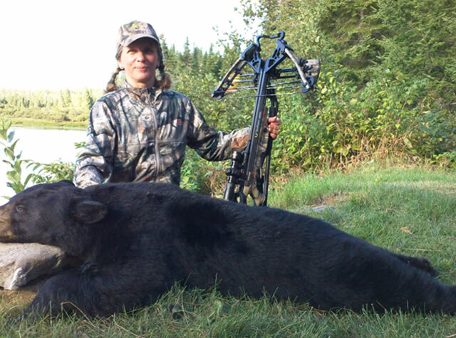 view of maine black bear hunting lodge surrounded by lake and forest