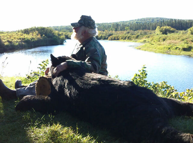 two bow hunters posing with killed black bear