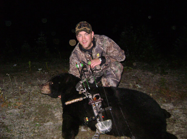 group of men on hunting trip posing with black bear kills from that night